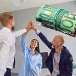 tre lavoratori felici 2 uomini 1 donna e rotolo di banconote da 100 euro